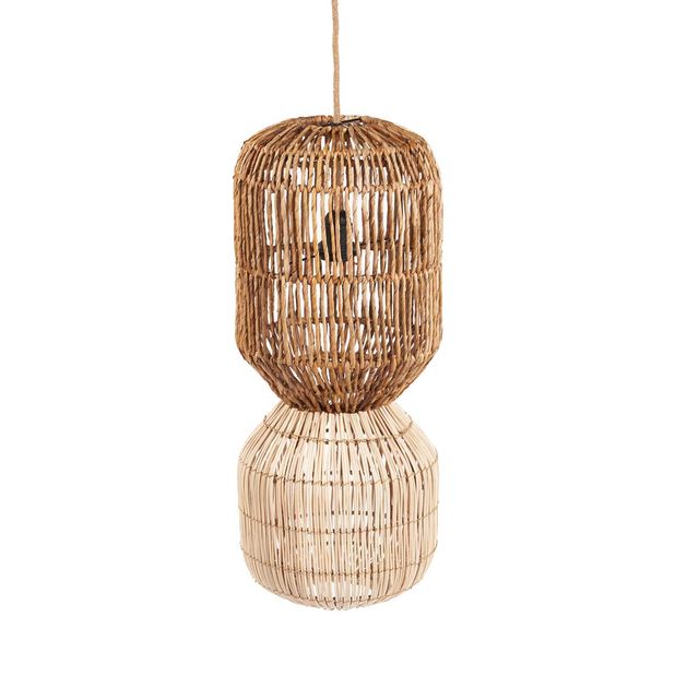 A two-tiered wicker pendant light in a natural tan color hangs in a modern outdoor patio setting next to a swimming pool, with a beige sofa and wooden table in the foreground.