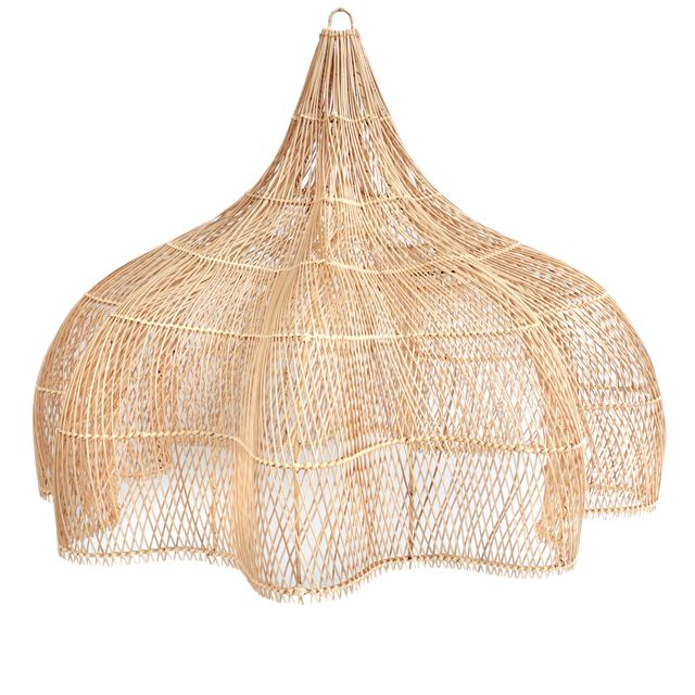 A large woven wicker pendant light hangs over a neatly made bed in a warm, rustic bedroom with beige walls, wooden ceiling beams, and a window with sheer curtains.