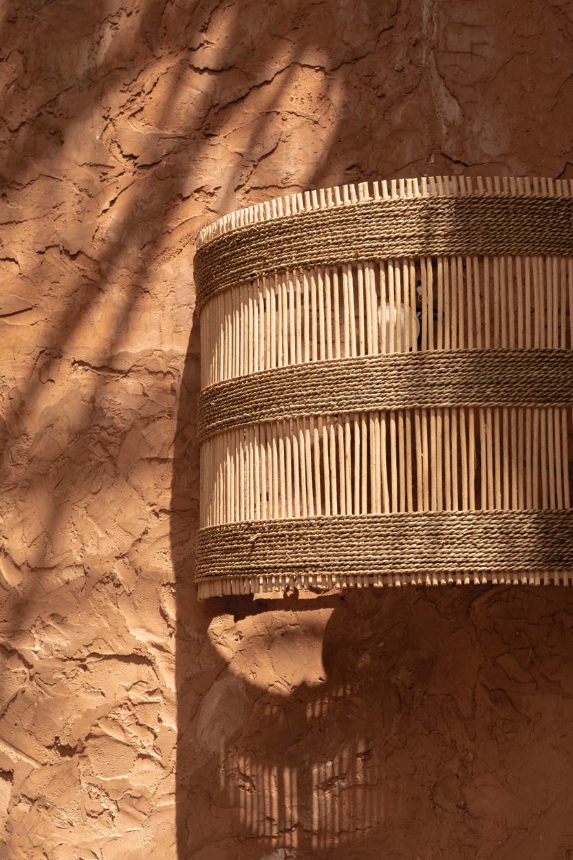 Woven wall lamp cover with jute straps on a white background