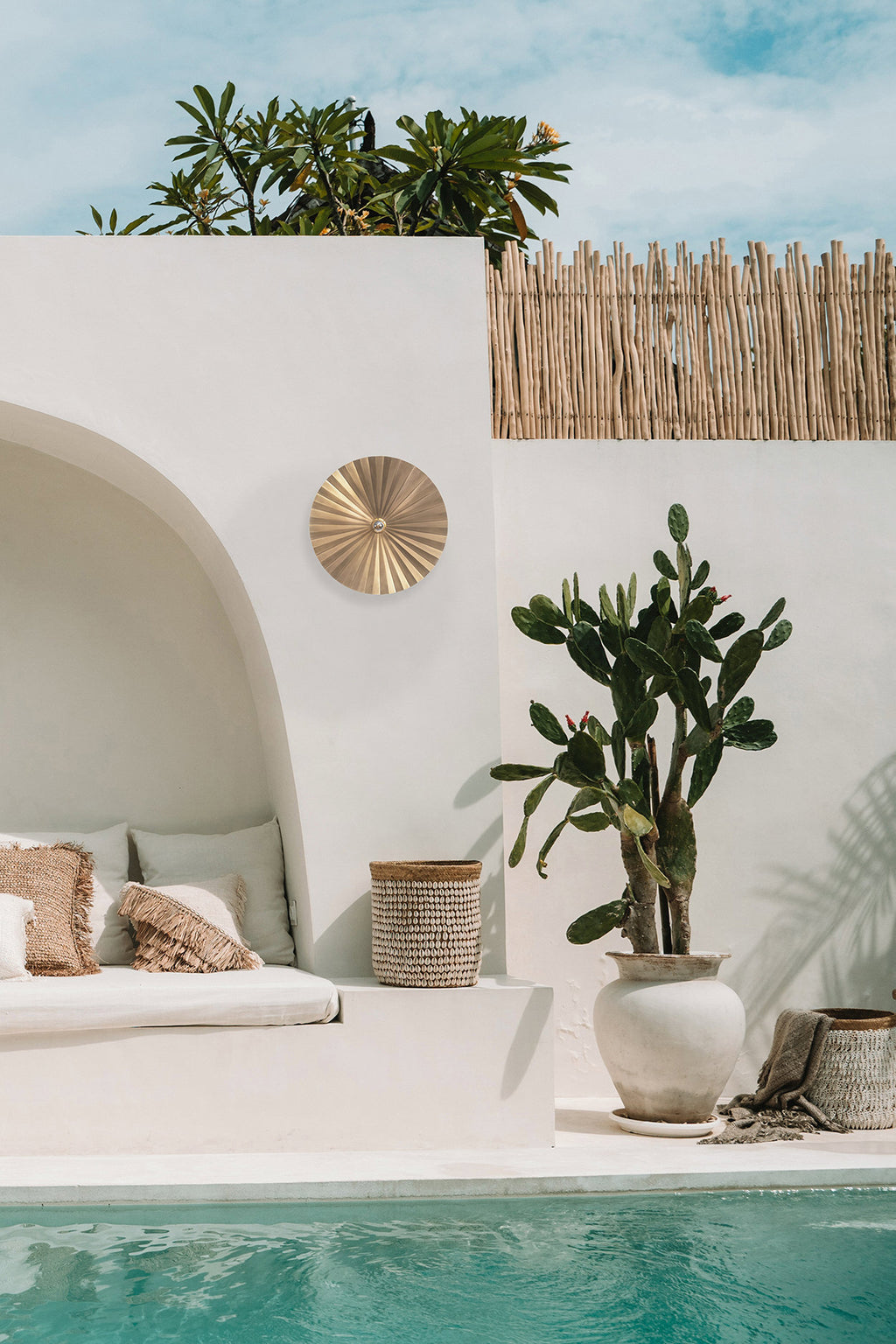 Decorative wall light fixture with gold sunburst design on a white background