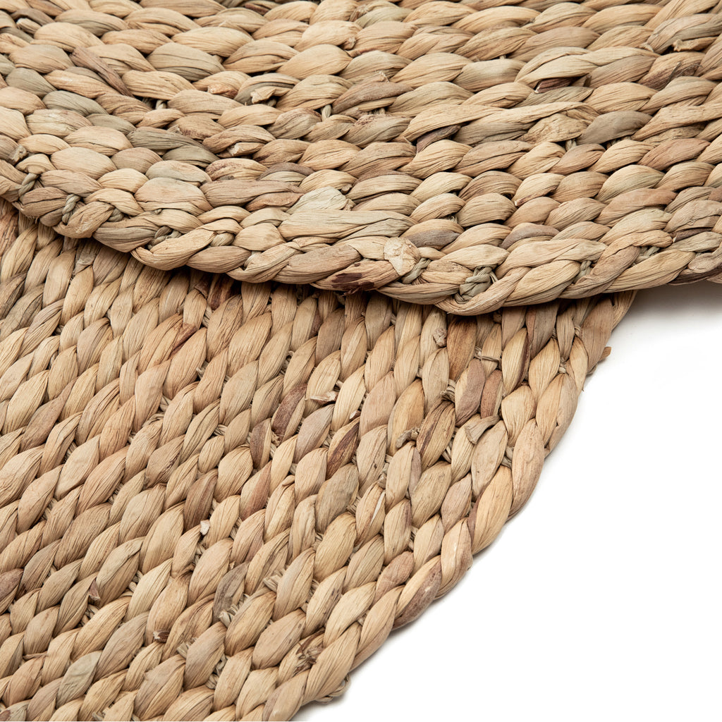 Round woven hyacinth fibre rug on a white background